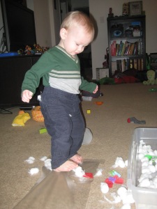 I taped down some contact paper sticky-side up to stick cotton balls and paper onto. Lewis discovered that it felt very interesting to walk across and get his feet stuck.