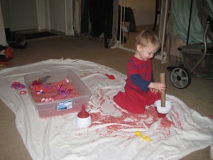 Valentine sensory bin with dyed rice and random red, pink, and purple objects.